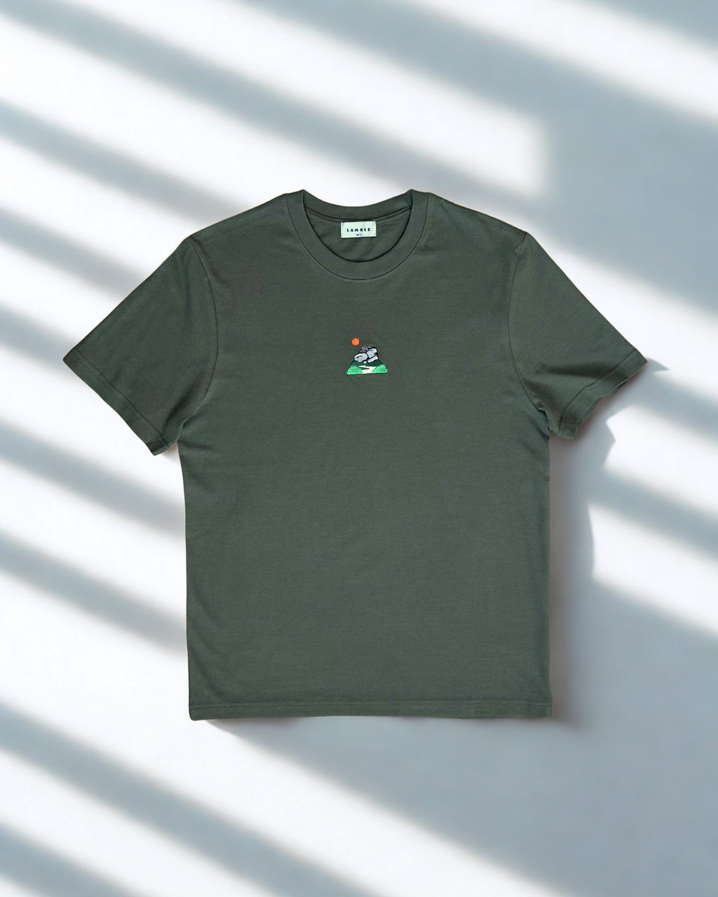 Peak District T-shirt flat lay with embroidered artwork of gritstone edges and hanging tag.